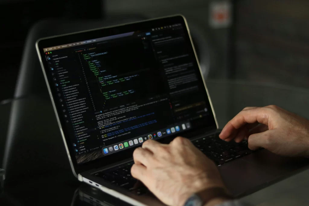 Manos escribiendo código en laptop - mantenimiento y desarrollo de software a medida
