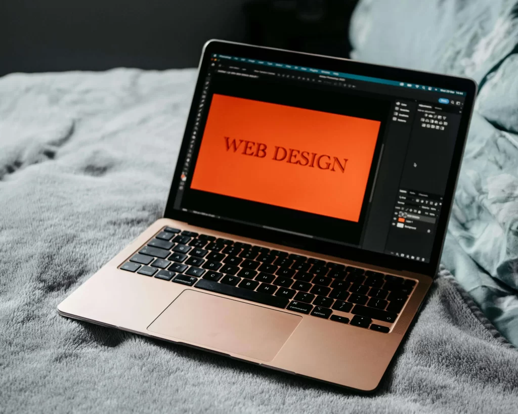 Ordenador portátil mostrando la palabra "web design" en pantalla, representando el rediseño de una página web