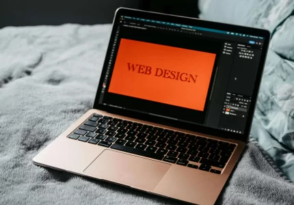 Ordenador portátil mostrando la palabra "web design" en pantalla, representando el rediseño de una página web
