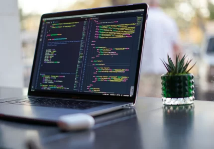 Portátil con código de un framework en desarrollo web sobre una mesa de trabajo