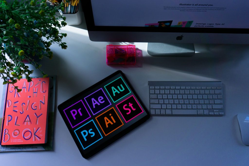 Tableta con los iconos de las herramientas de Adobe sobre una mesa de trabajo de diseño