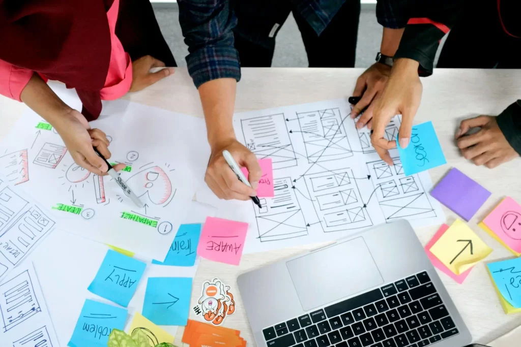 Equipo de diseño dibujando wireframes de una web sobre papel rodeado de notas adhesivas de colores