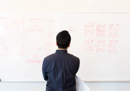 Profesional de espaldas frente a un diagrama de flujo dibujado en una pizarra