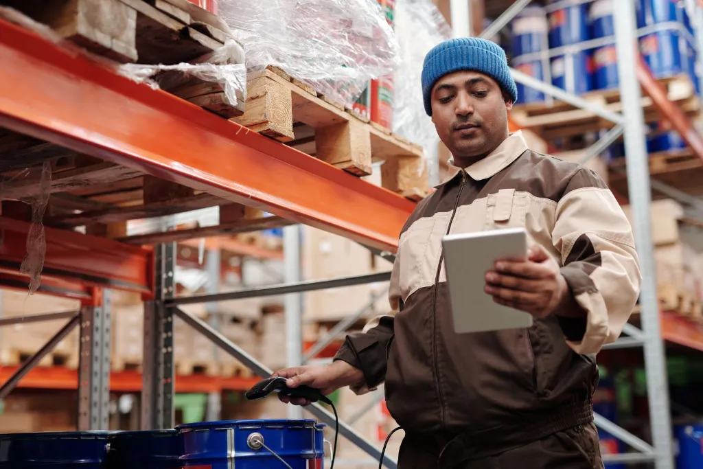Trabajador consultando una tablet entre estanterías de un almacén